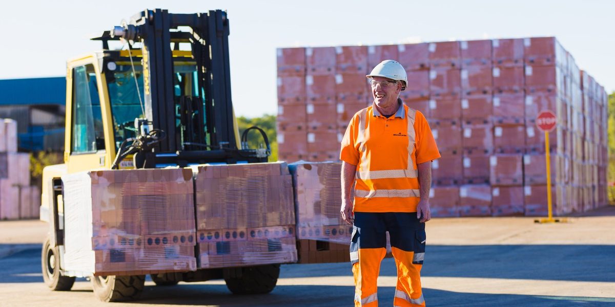 Wienerberger UK employee standing in front of pallet of bricks and forklift